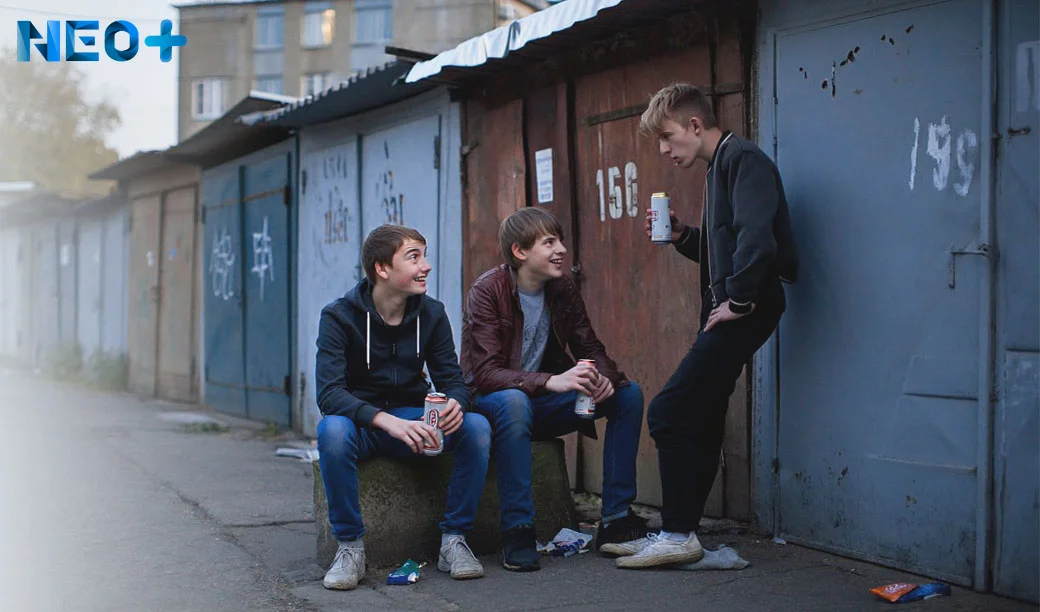 Группа подростков пьет пиво за гаражами